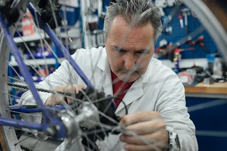 Un bénéficiaire du projet de EA Cycles règlent le poignon de vitesse d'un vélo.